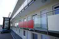 Rustfrit balkon gelænder med udfyldning i klart hærdet sikkerhedsglas eller højtrykslaminat (HPL) farvede plader