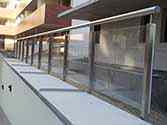 Glas rækværk med rustfrie stolper og håndlister ved indgangen til den underjordiske parkeringsplads