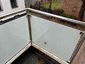 Glas rækværk med rustfrie stolper og håndlister. Glaspaneler monteret med glasklemmer i rustfrit stål