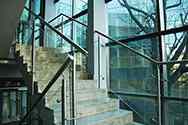 Gelænder til trappe i glas og rustfrit stål. Højglanspoleret rørformet stolper og håndliste. Udfyldning med klart hærdet sikkerhedsglas