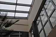 Glastag der dækker et væksthus i kontorbygningen. Glaspanel sætte oven på en stålramme i varmforzinket, pulverlakeret stål monteret på taget.